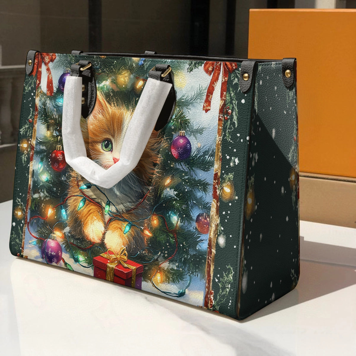 Glänzende Ledertasche unter dem Weihnachtsbaum mit Weihnachtskätzchen